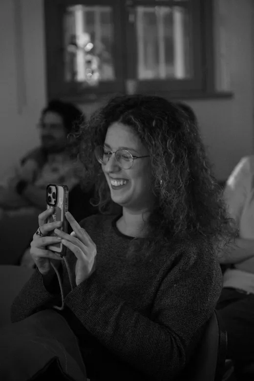 Una ragazza in sala, col telefono in mano, sorride mentre ascolta una storia.